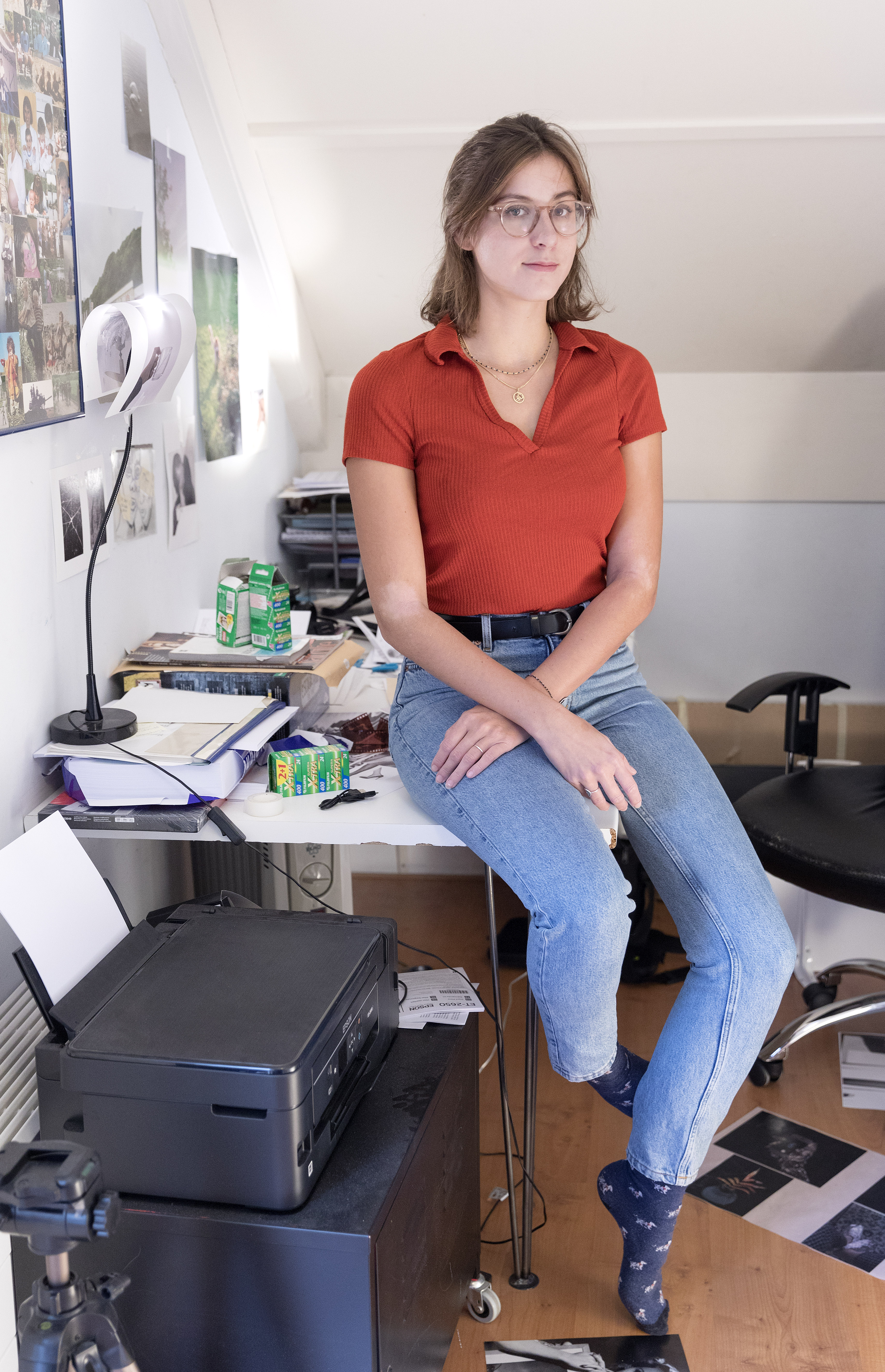 Laura van Erp zit op het puntje van haar bureau met foto's en schetsen om haar heen