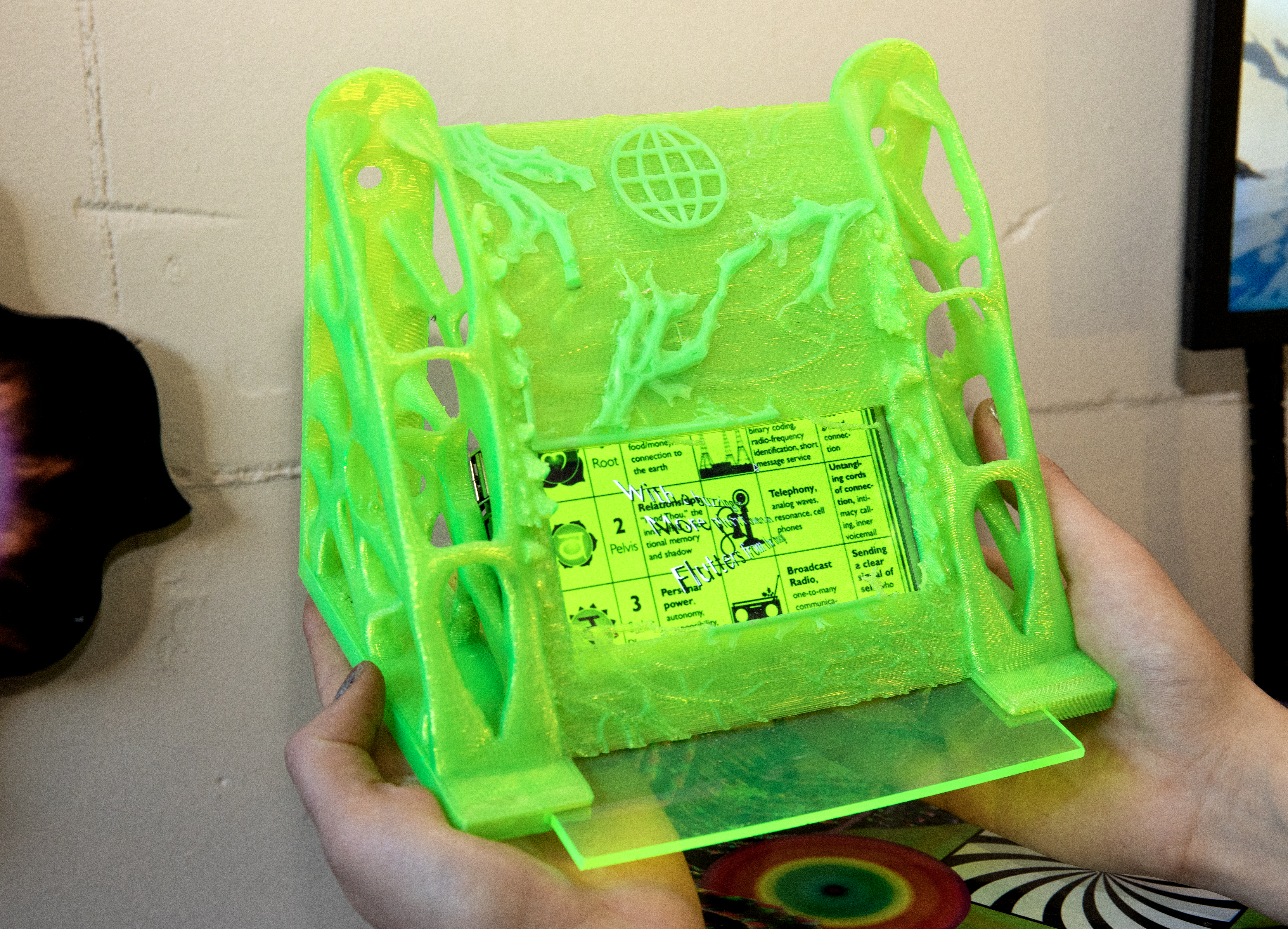 Een foto van een Haiku generator; een klein beeldscherm omhuld door een houder van fluoriserend groen plastic
