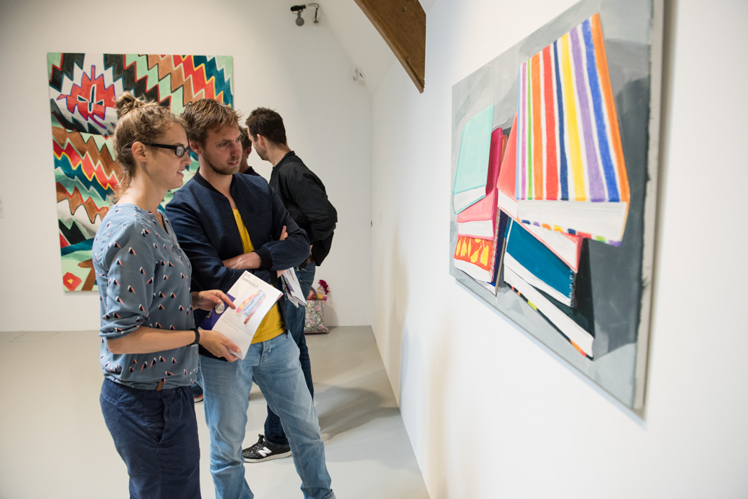 bezoekers bekijken schilderij in tentoonstelling